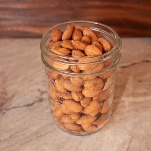 Mason jar filled with raw, soaked and dehydrated almonds