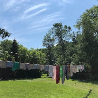 clothes hanging on an outdoor clothesline, with the blue sky and green grass in the background