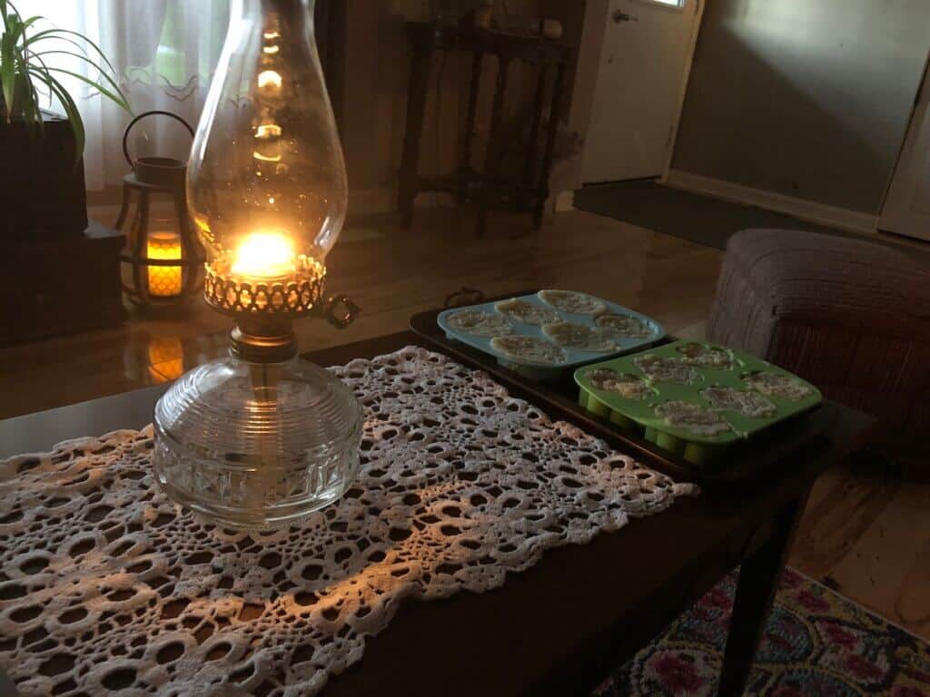A lit oil lamp, with a doiley under it, on a coffee table. 