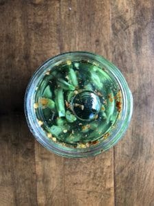 glass fermentation weight on top of a jar of green beans