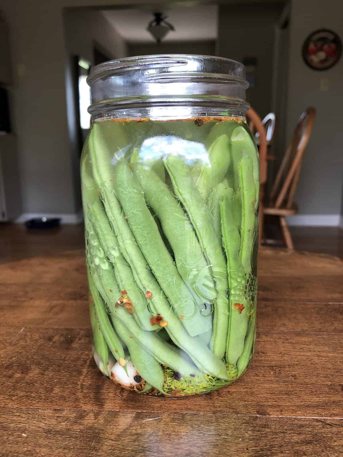 Side view of green beans in a mason jar, covered in brine