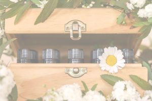 essential oils in a wooden box with daisies