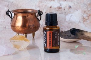 bottle of frankincense essential oil next to an urn with a chunk of frankincense resin