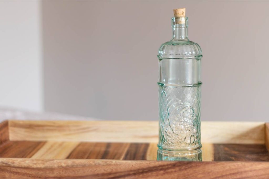 Empty green glass bottle with a cork, on a wooden tray