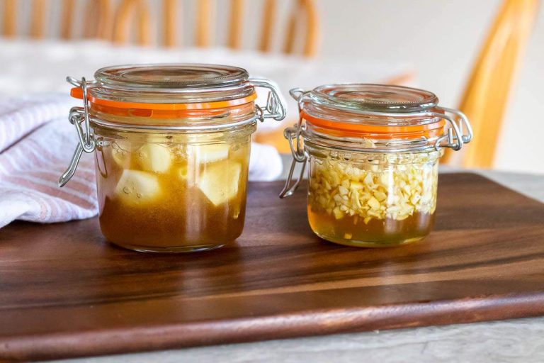 a jar of whole garlic cloves in honey, next to a jar of chopped garlic in honey.