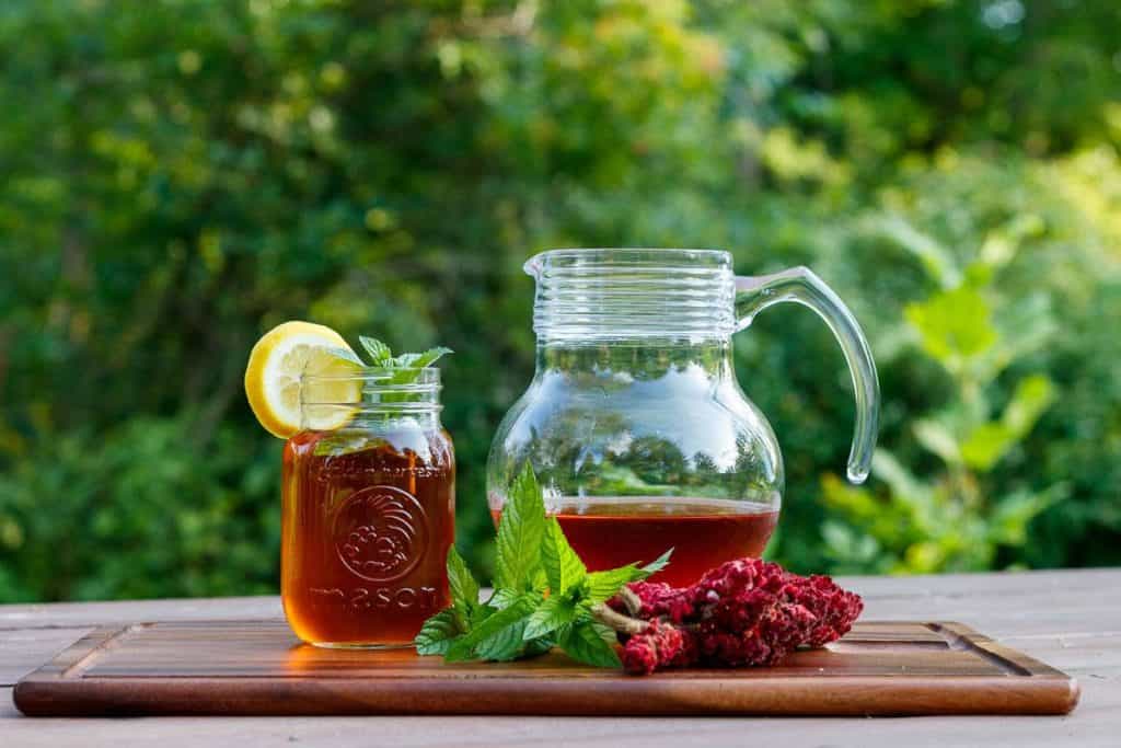 sumac lemonade in a glass next to a pitcher