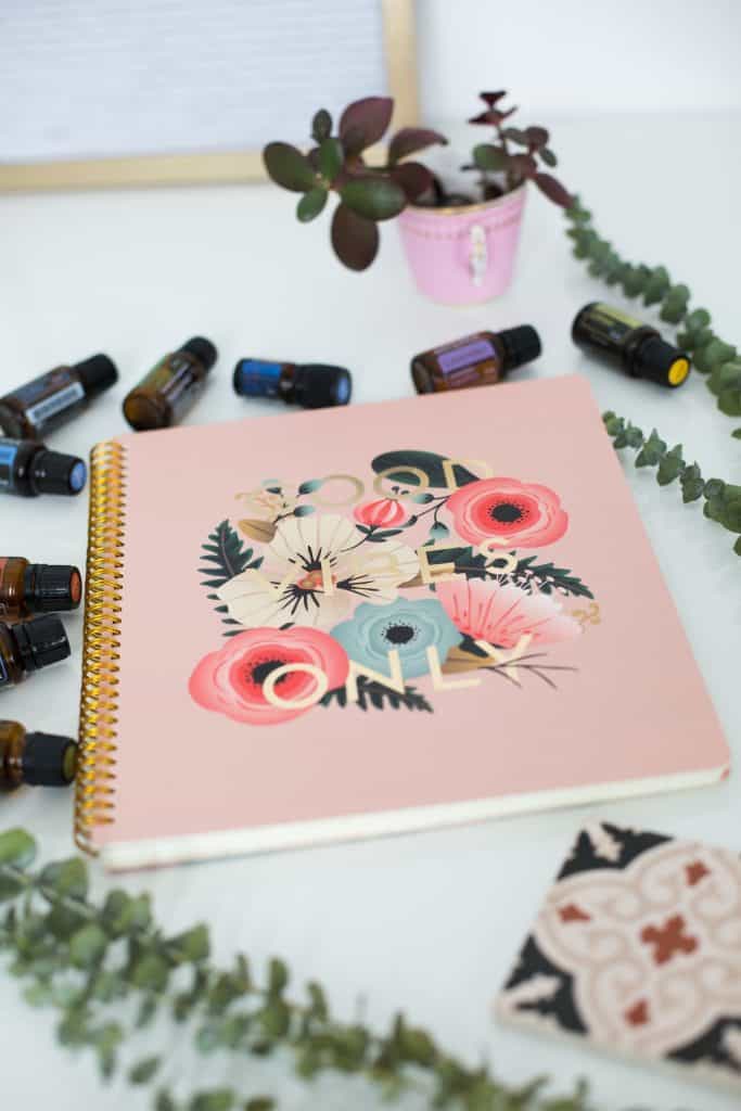 notebook with floral cover next to essential oil bottles